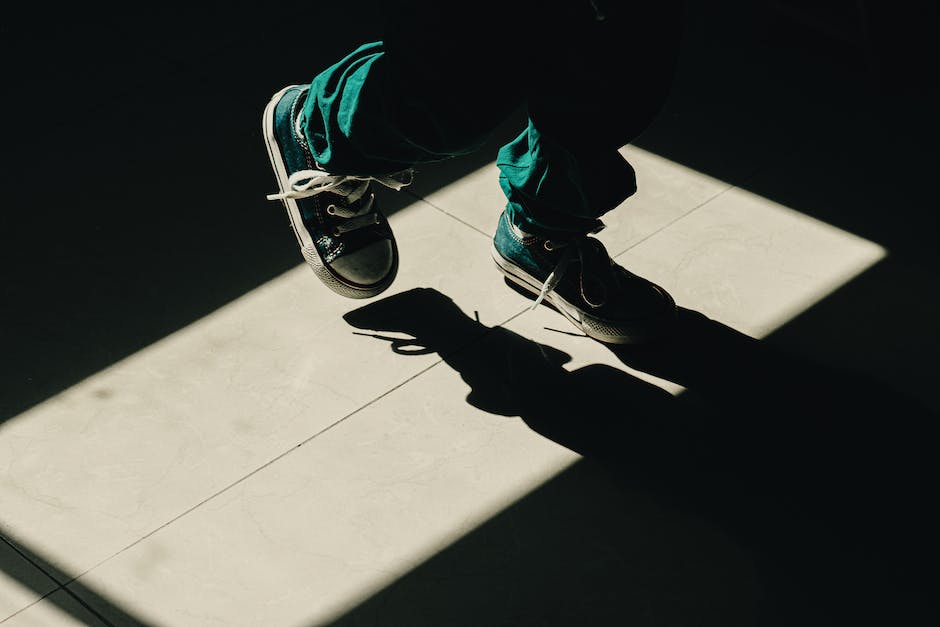 A young boy is trying on two pairs of shoes, one pair of slip-on shoes and the other a pair of lace-up shoes, to decide which one he should wear.